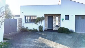 Un edificio moderno de dos pisos con fachada de piedra, una puerta delantera oscura y un ventanal pequeño.
