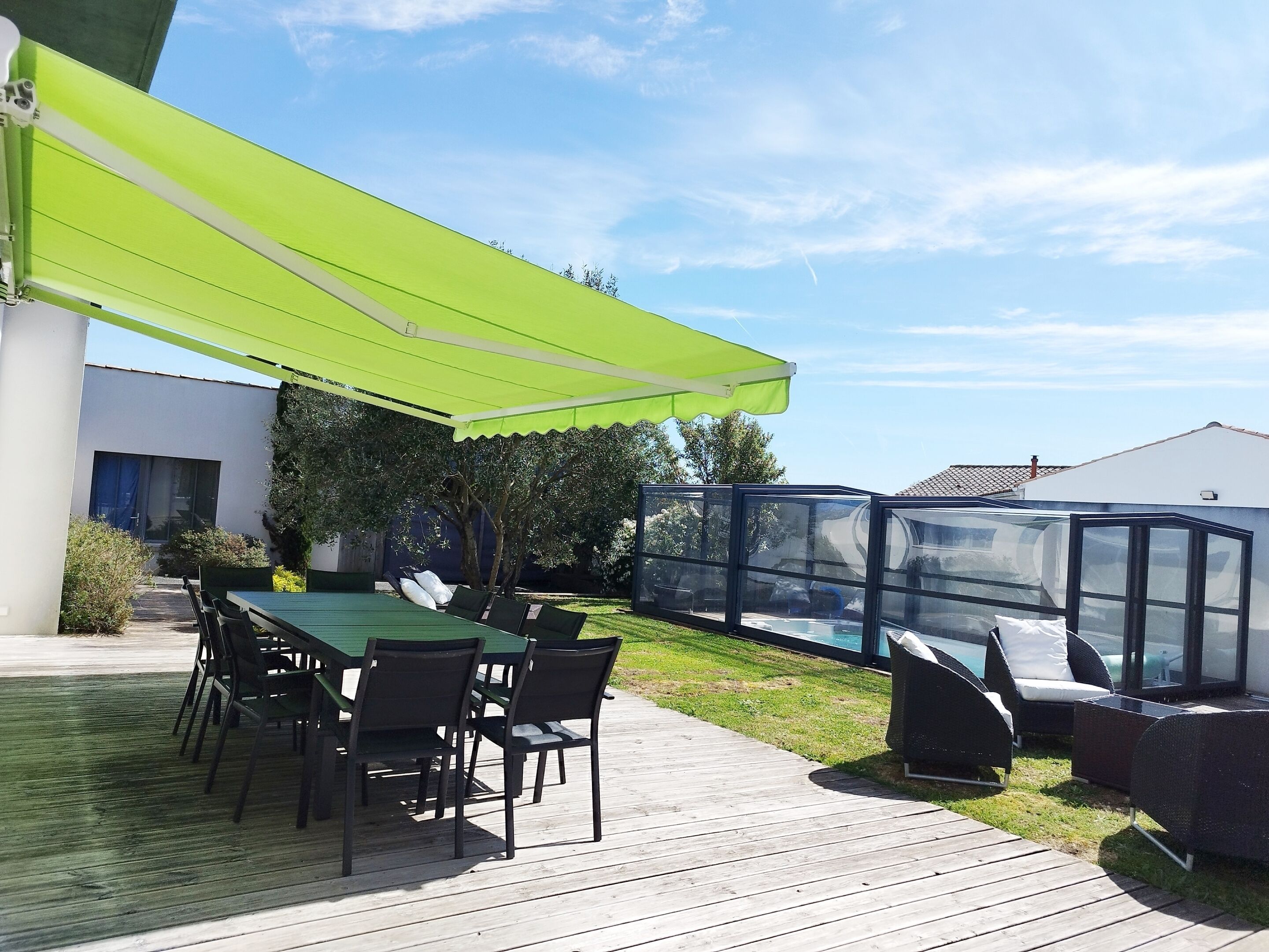 A patio with a green awning, a pool, and outdoor furniture.
