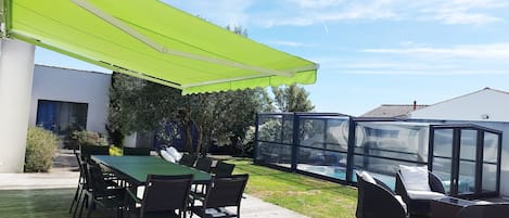 A patio with a green awning, a pool, and outdoor furniture.