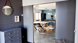 Un interior moderno con comedor, un espejo, panel de control en la pared y una escalera.