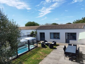 Une maison moderne dotée d’une piscine, d’un espace salon extérieur et d’un patio.