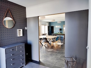 A modern interior with a dining area, a mirror, a wall-mounted control panel, and a staircase.