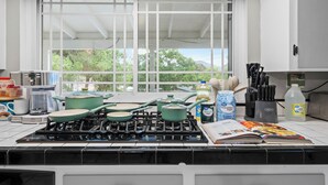 A kitchen with a gas stove, pots, a coffee maker, and a window with a view of trees. - King Bed, 6 Parking, 6 Beds, Big Yard (Spring Valley)