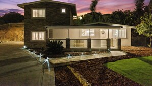 A two-story house with a stone facade, a covered porch, and a landscaped front yard with a pathway and lights. - King Bed, 6 Parking, 6 Beds, Big Yard (Spring Valley)