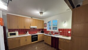 A kitchen with wooden cabinets, a microwave, a sink, and a window. - T3 duplex house, atypical, with wooded garden, very large terrace and parking space (Toulouse)