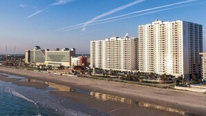 Een kusthotel met meerdere hoge gebouwen, een strand en een steiger.