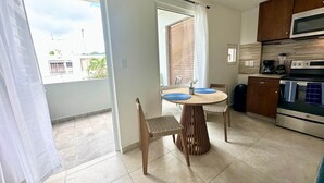 A modern kitchen with a dining area, featuring a round table, wooden chairs, a built-in oven, and a microwave. - Centrally located Simpson bay 1bdr apt (1-4A) (Simpson Bay)