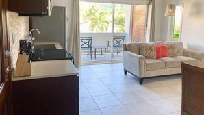 A modern kitchen with a sink and cabinets, a dining area with a table and chairs, and a living room with a sofa and a ceiling fan. - Blue Sky Apt in the middle of Simpson Bay-GENERATOR(1-3A) (Simpson Bay)