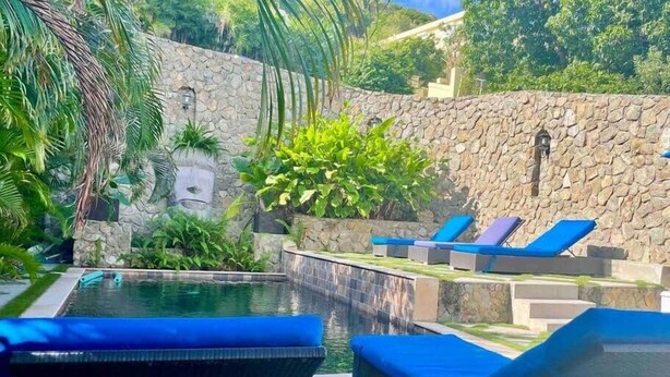A swimming pool with lounge chairs and a stone wall. - Blue Sky Apt in the middle of Simpson Bay-GENERATOR(1-3A) (Simpson Bay)