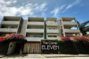 A multi-story building with balconies, a gated entrance, and a sign reading "The Corner ELEVEN".