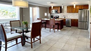 A modern kitchen with a dining area, featuring a glass table, wooden chairs, and a stainless steel refrigerator. - Oasis Apartment in Simpson bay (2-3) (Simpson Bay)
