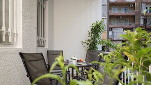 A balcony with a table and chairs, a potted plant, and a view of a residential building. - Garage Studio in Mar Mikhael (Beirut)