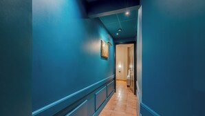 A hallway with blue walls and a tiled floor, leading to a room with a door. - Daplace - Antica Casa Coppo  (Venice)