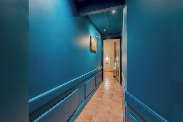A hallway with blue walls and a tiled floor, leading to a room with a door. - Daplace - Antica Casa Coppo (Venice)