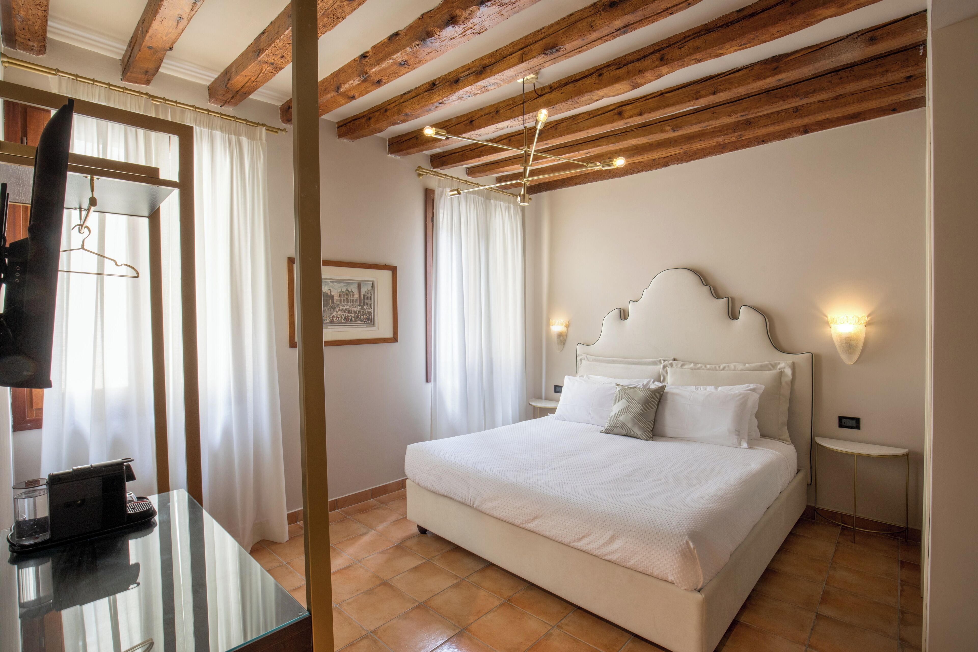 Een slaapkamer met een bed, nachtkastjes, een spiegel en een kapstok.