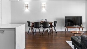 Un salon moderne comprenant un coin repas, un plancher en bois, un téléviseur à écran plat et un canapé.