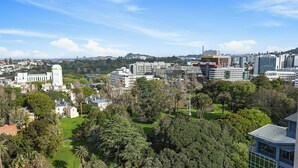 Un paysage urbain avec des bâtiments modernes, une grande tour blanche et de la verdure environnante.