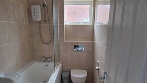Um banheiro com banheira, vaso sanitário e chuveiro.