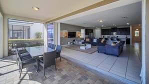 A spacious living area with a dining table and chairs, a sofa, and a kitchen in the background. - Stunning Kissimmee Home  Private Pool Near Disney Parks (Kissimmee)