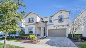 A two-story house with a stone archway entrance, a garage, and a paved driveway. - Stunning Kissimmee Home  Private Pool Near Disney Parks (Kissimmee)