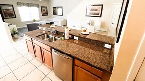 A kitchen with granite countertops, stainless steel appliances, and a ceiling fan. - 5BR Pool+Hot Tub Home Kissimmee Near Disney WDW (Kissimmee)