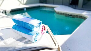 A poolside area with a lounge chair and a towel. - 5BR Pool+Hot Tub Home Kissimmee Near Disney WDW (Kissimmee)