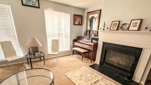 A living room with a fireplace, piano, and a glass table. - Nice 2 bedroom home with backyard only 15 mins outside of Atlanta. (Detroit)