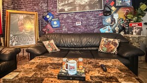A living room with a brick wall, a framed poster, a couch, and a coffee table with a mug and remote control. - Nice 2 bedroom home with backyard only 15 mins outside of Atlanta. (Detroit)
