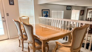 A dining area with a wooden table and upholstered chairs, a white railing, and a door with a phone. - Nice 2 bedroom home with backyard only 15 mins outside of Atlanta. (Detroit)