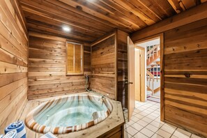 Una cabaña de madera con jacuzzi, paredes de madera, una ventana y una escalera que sube a un nivel superior.