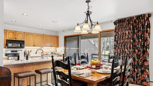 Una cocina moderna con armarios de madera, una isla central y una zona de comedor con mesa y sillas de madera.