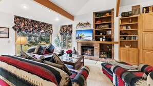 Una sala de estar acogedora con chimenea, asientos cómodos y una estantería.