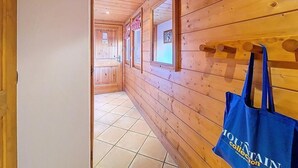 Ein Holzbodenkorridor mit einer blauen Tasche an der Wand, der zu einem Raum mit Fliesenboden führt.