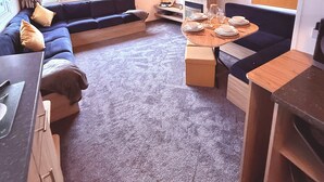 Un espai habitable reduït amb sofà, taula de dinar i zona de cuina.