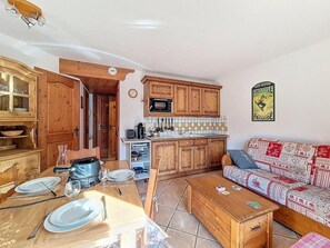 A cozy kitchen with wooden cabinets, a microwave, and a dining area set for four. - 100m from ski slopes, Ground floor, swimming pool, tv, ski locker, 35m², Les Menuires (Les Menuires)