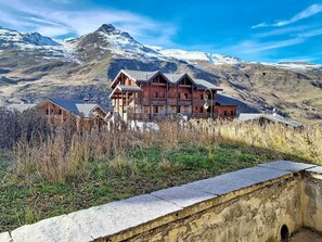 A chalet-style building with multiple balconies, set against a mountainous backdrop. - 100m from ski slopes, Ground floor, swimming pool, tv, ski locker, 35m², Les Menuires (Les Menuires)