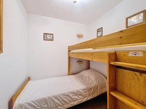 A small, single-bed room with a bunk bed and a wooden headboard. There are two framed pictures on the wall and a small shelf above the bed. - 100m from ski slopes, Ground floor, swimming pool, tv, ski locker, 35m², Les Menuires (Les Menuires)