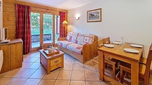 Ein gemütliches Wohnzimmer mit einer Couch, einem Holzespeisetisch für zwei Personen und einem kleinen Holzschrank.