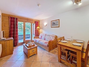 A cozy living room with a sofa, a wooden dining table set for two, and a small wooden cabinet. - 100m from ski slopes, Ground floor, swimming pool, terrace, tv, ski locker, 32m², Les Menuires (Les Menuires)