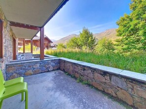 A covered outdoor area with stone walls, a concrete floor, and a view of mountains and greenery. - 100m from ski slopes, Ground floor, swimming pool, terrace, tv, ski locker, 32m², Les Menuires (Les Menuires)