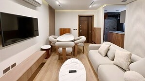 Un salon moderne doté d’un téléviseur à écran plat, d’une table basse ronde, d’un canapé et d’un coin repas avec des chaises.