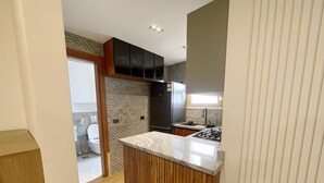Une cuisine moderne dotée d’un îlot central, de meubles de rangement en bois et d’un four encastré.