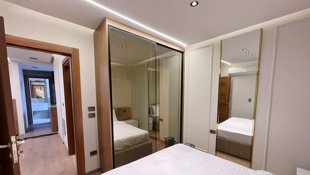 Une chambre d’hôtel moderne dotée d’un grand lit, d’un dressing et d’une salle de bain avec un miroir.