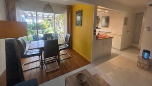 A modern living room with a dining area, a kitchen, and a view of the outdoors. - Cocon Tropical (Sainte-Anne)