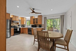 A modern kitchen with wooden cabinets, stainless steel appliances, and a dining area with wooden chairs. - 5BR + Game Room Bridge Park + Zoo Sleeps 12 (Columbus)