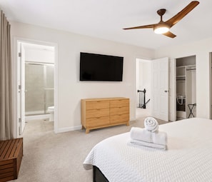 A bedroom with a bed, a wooden dresser, a television, a ceiling fan, and a walk-in closet. - 5BR + Game Room Bridge Park + Zoo Sleeps 12 (Columbus)