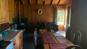 A wooden cabin interior with a kitchen, dining area, and seating space. - Beautiful Family Cabin in Pucón (Pucon)
