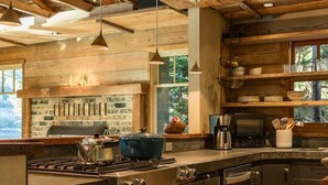 Una cucina rustica con travi in legno, una grande isola con un piano cottura e uno schienale in pietra.