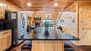 A kitchen with wooden walls, a central island, and a refrigerator. - Heated Pool (seasonal), Hot Tub, Game Room, & Mountain Views – Sleeps 12 (Sevierville)