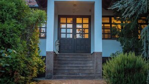 Ein Haus mit einer dunklen Holztür, einer kleinen Statue vor der Treppe und einem Licht darüber.